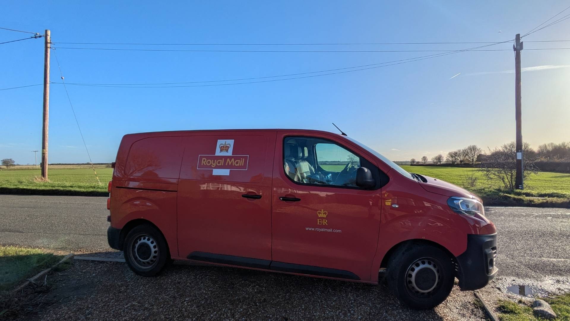 A Royal Mail van parked beside a fenland country road on a bright winter morning — Mike's previous job before founding Hunt 'n' Haul