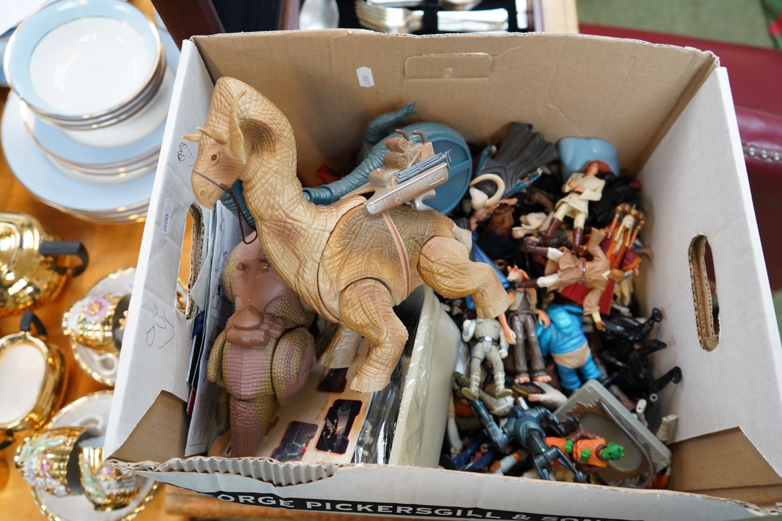 A second cardboard box of vintage Star Wars action figures and creatures — a large Tauntaun, an Ewok village, dozens of original-trilogy figures spilling out