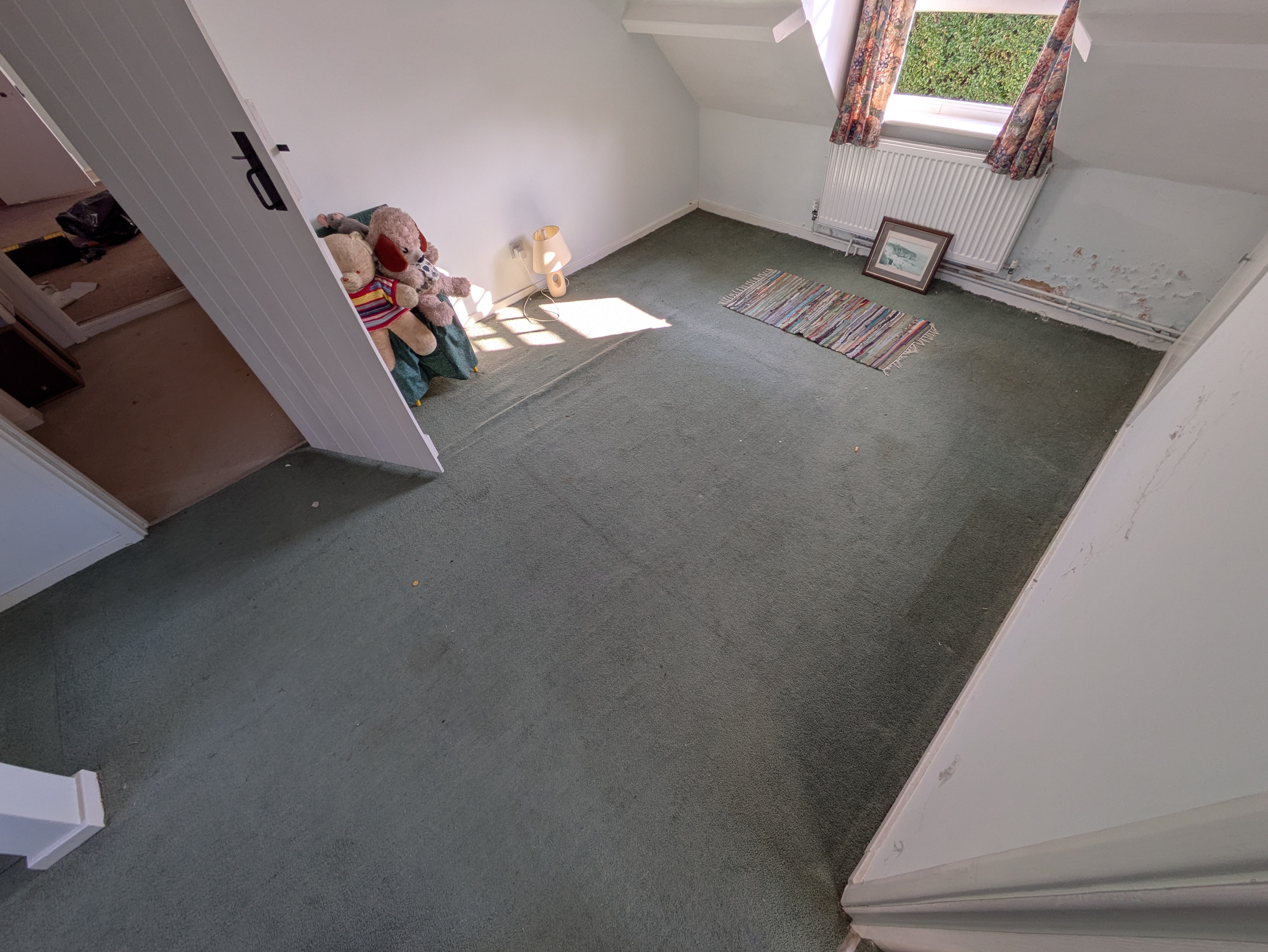 The same bedroom cleared down to the carpet, light streaming through the dormer window, only a teddy bear and a small framed picture left to keep